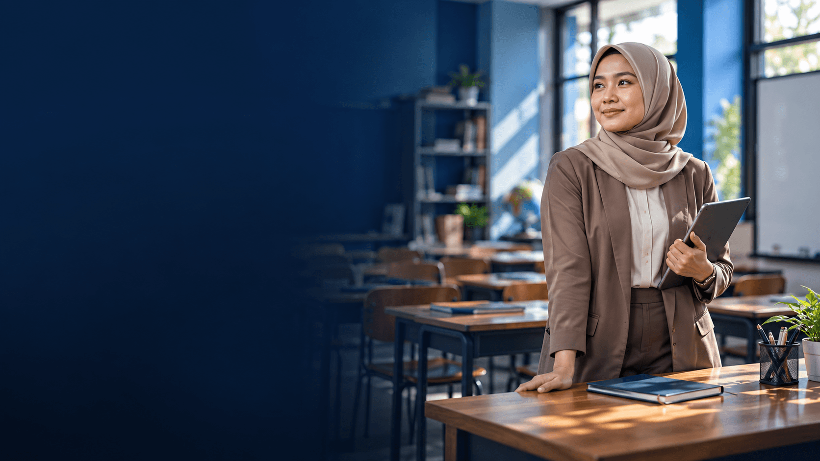 Guru berdiri di ruang kelas modern sambil memegang tablet